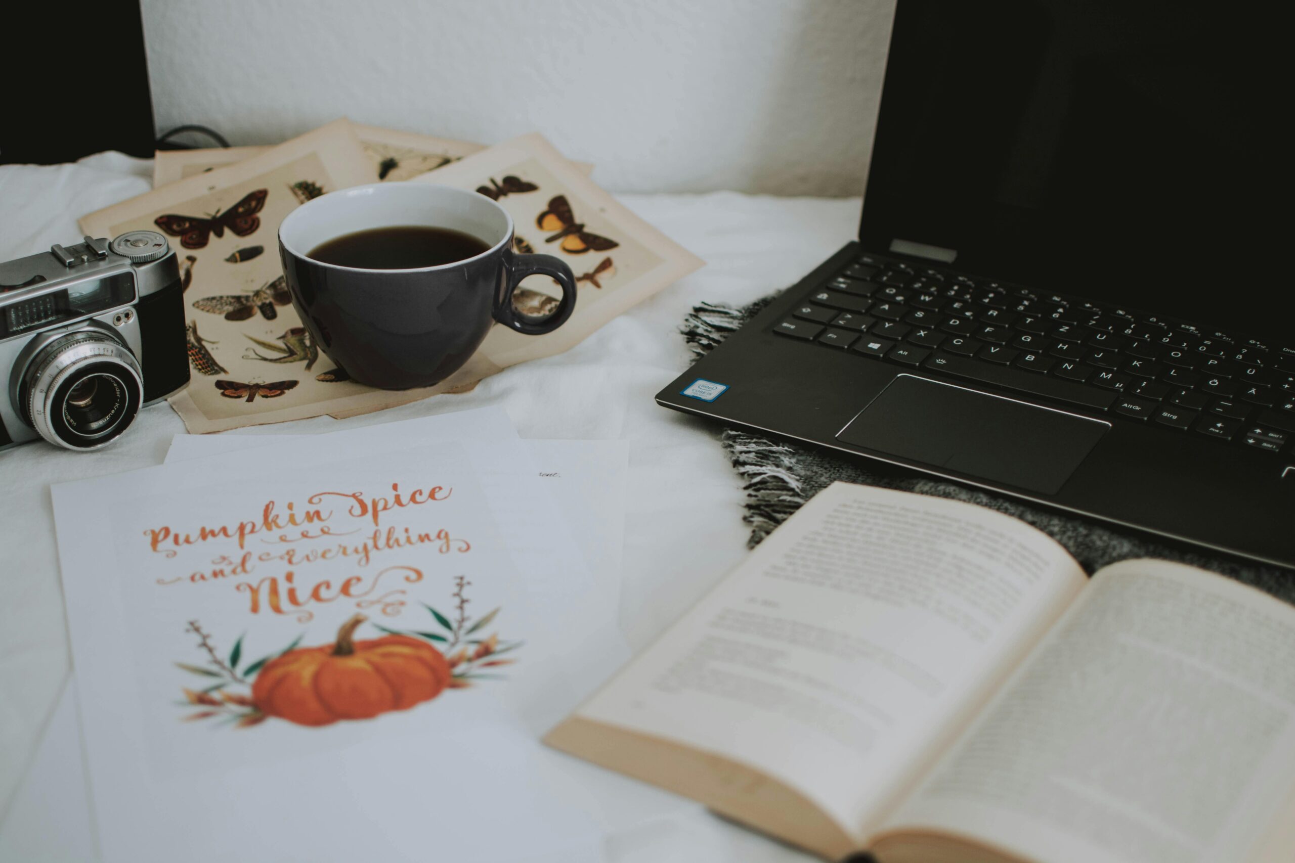 A cozy indoor workspace featuring a laptop, camera, coffee cup, and open books for a productive atmosphere.