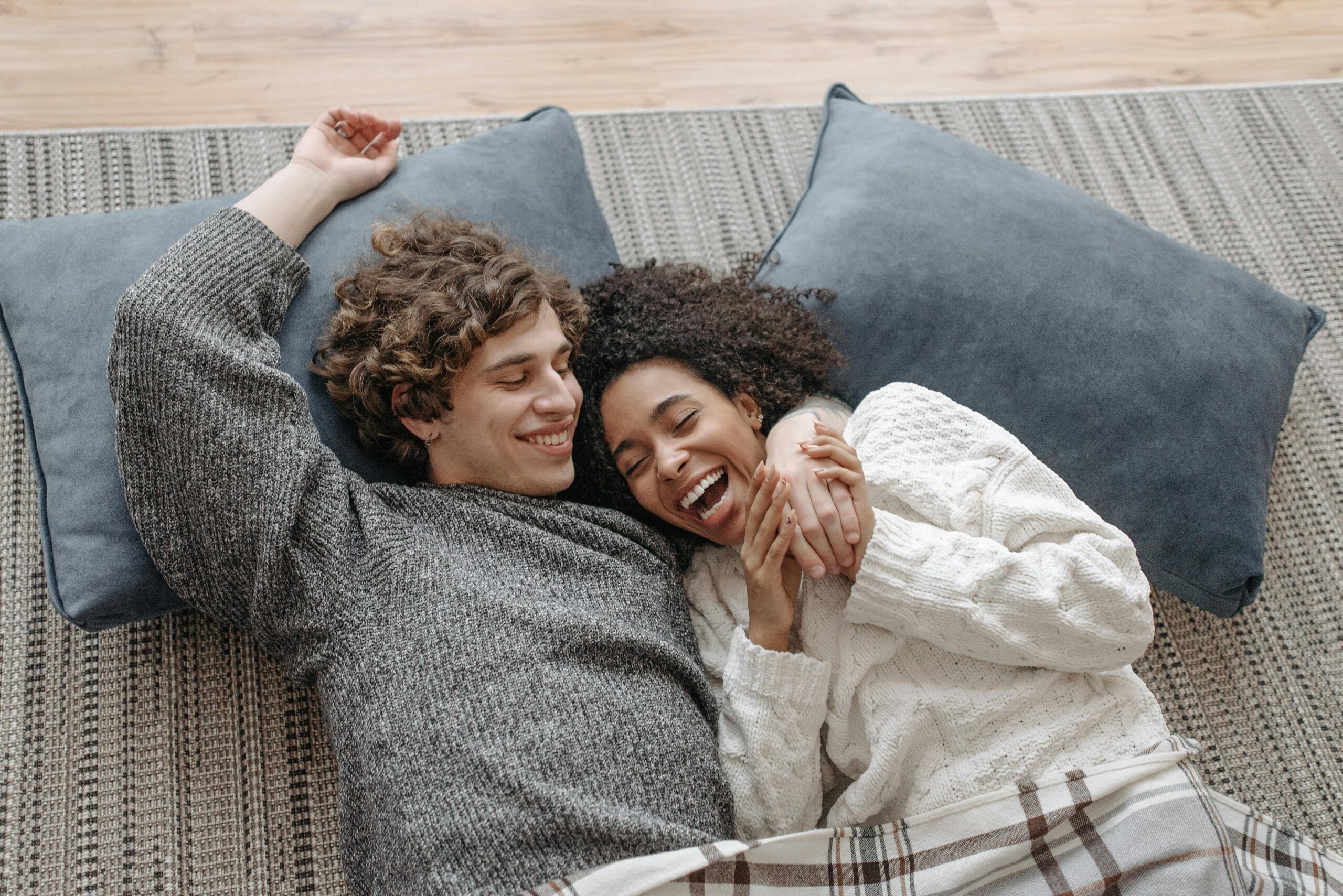A happy couple snuggling on a cozy indoor setting, enjoying a relaxed winter day.