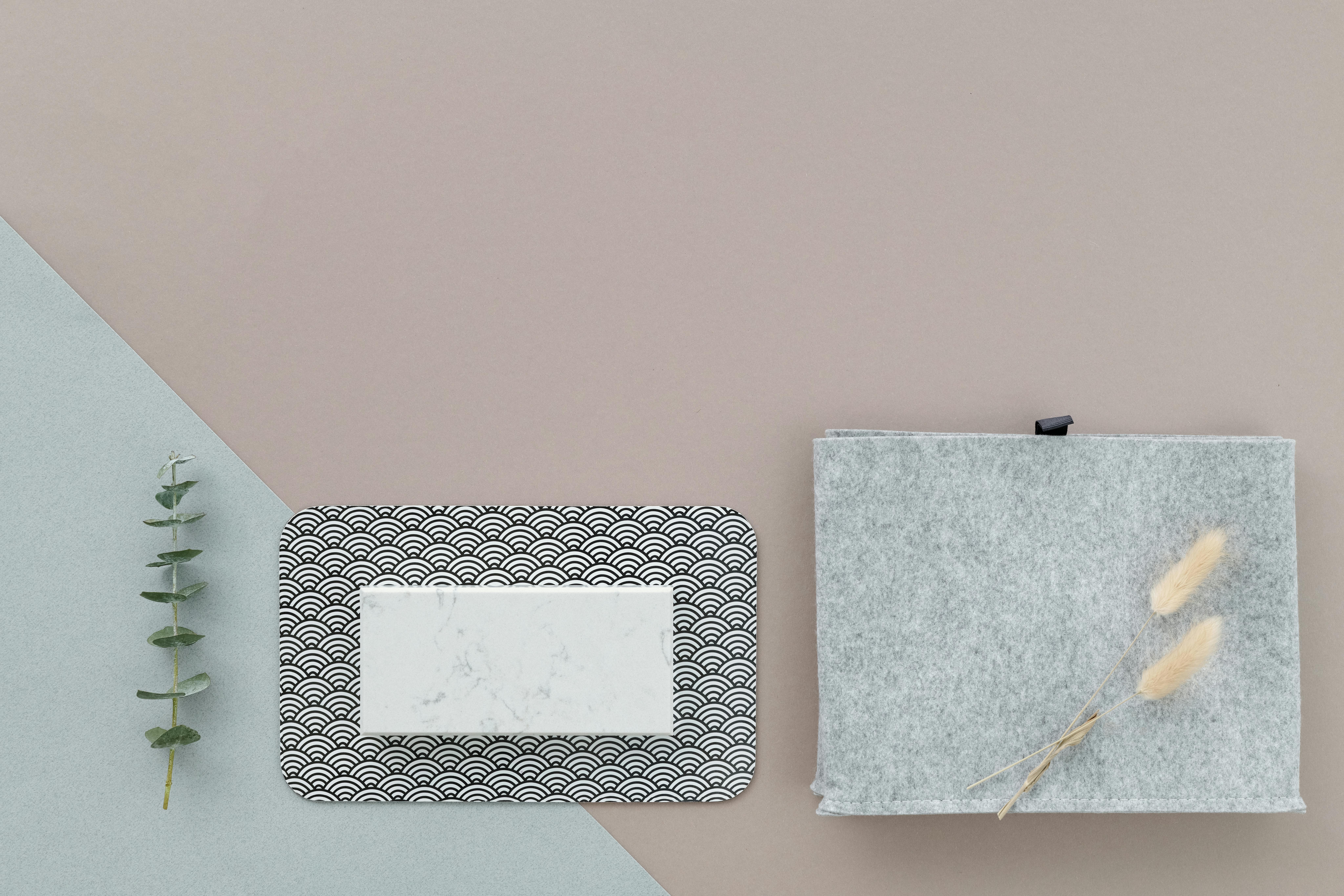 A minimalist flat lay featuring a patterned tray, felt fabric, and dry plants.
