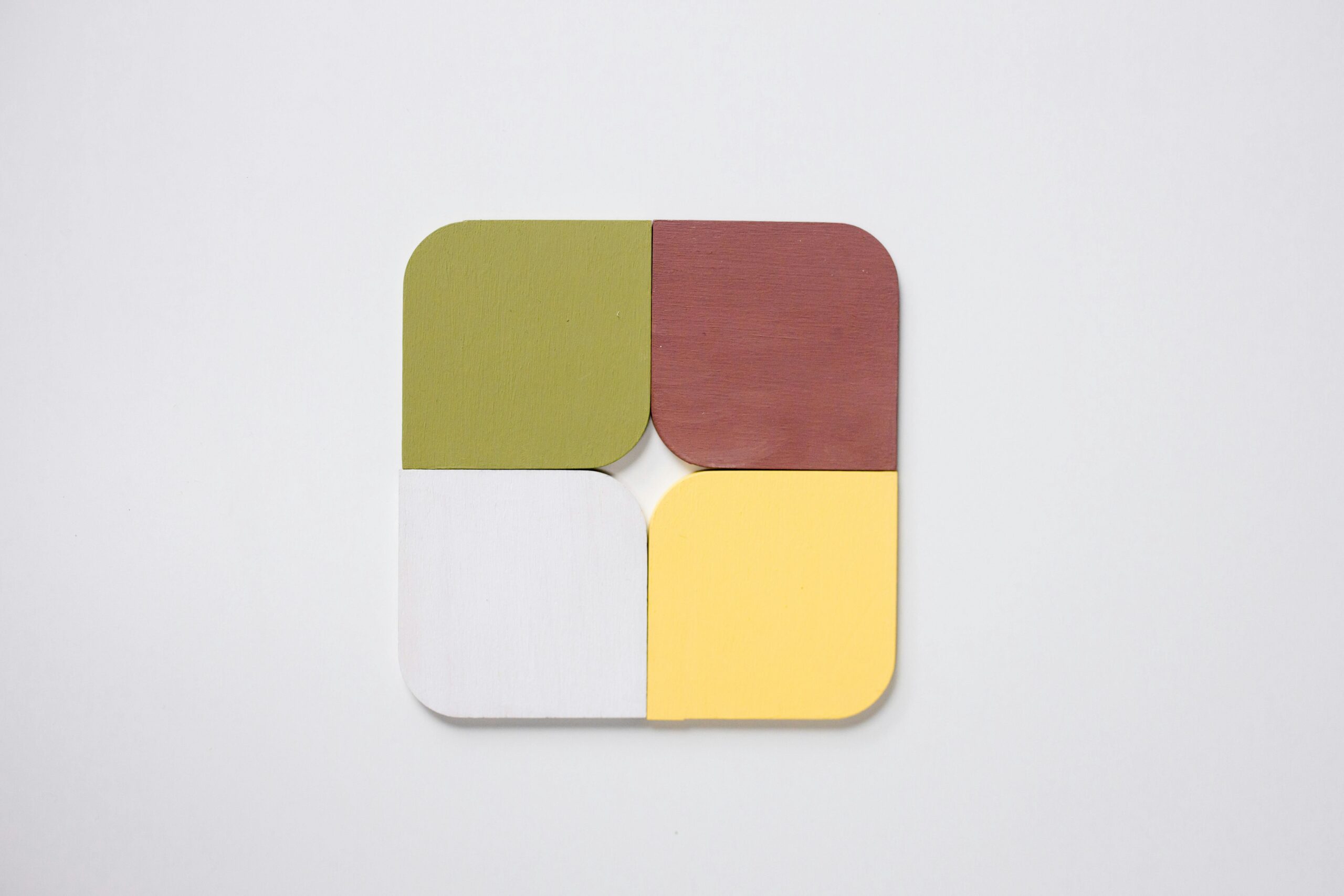 A minimalist geometric pattern design featuring four colorful sections on a white background.