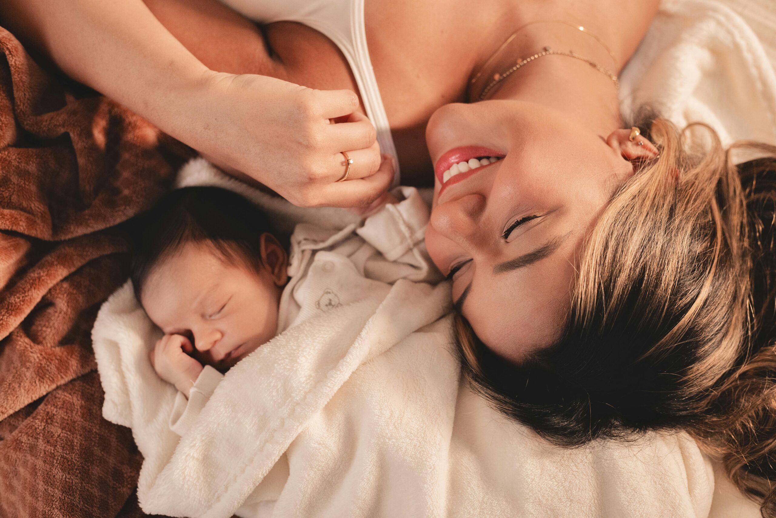 A mother and her newborn baby lying peacefully together in a cozy blanket.