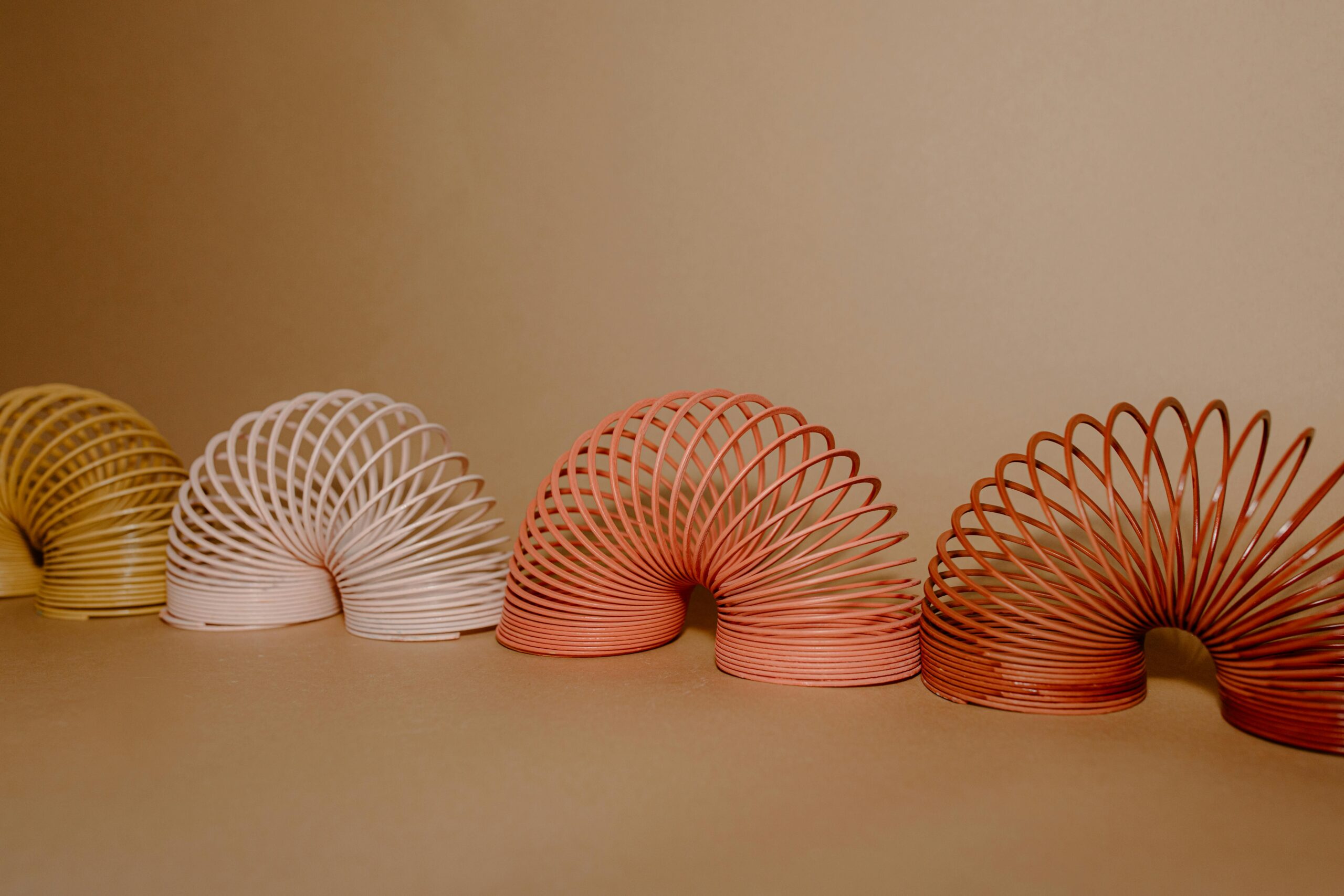 A vibrant row of Slinkies displaying gradient rainbow colors on a neutral backdrop.