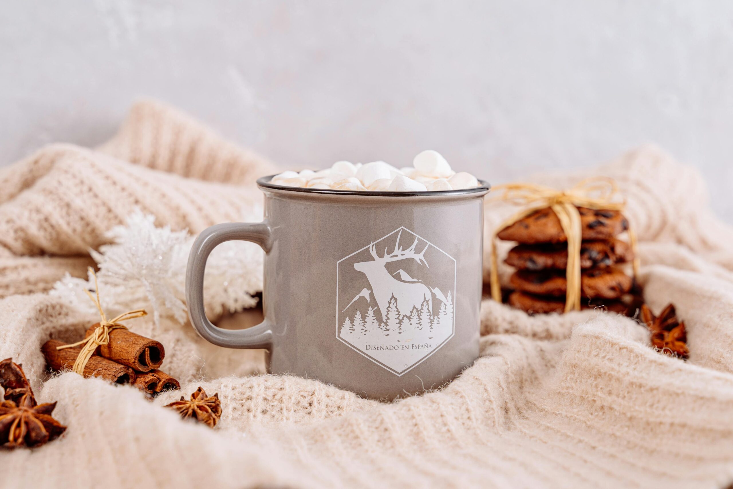 A warm and cozy setting with a mug of marshmallows, cinnamon, and cookies, perfect for winter.