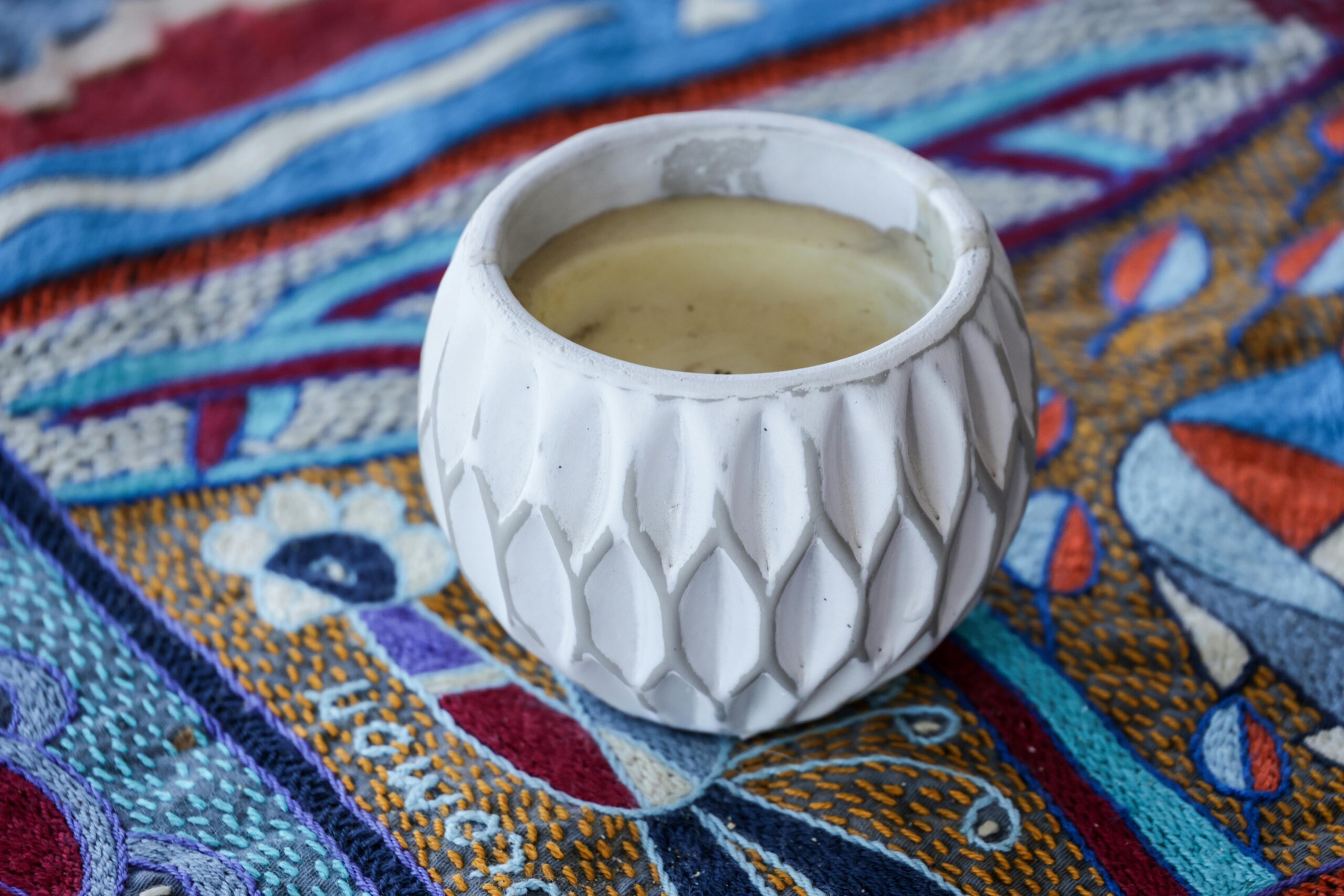 Белый керамический подсвечник на яркой текстурированной ткани, добавляющий эстетическое очарование.