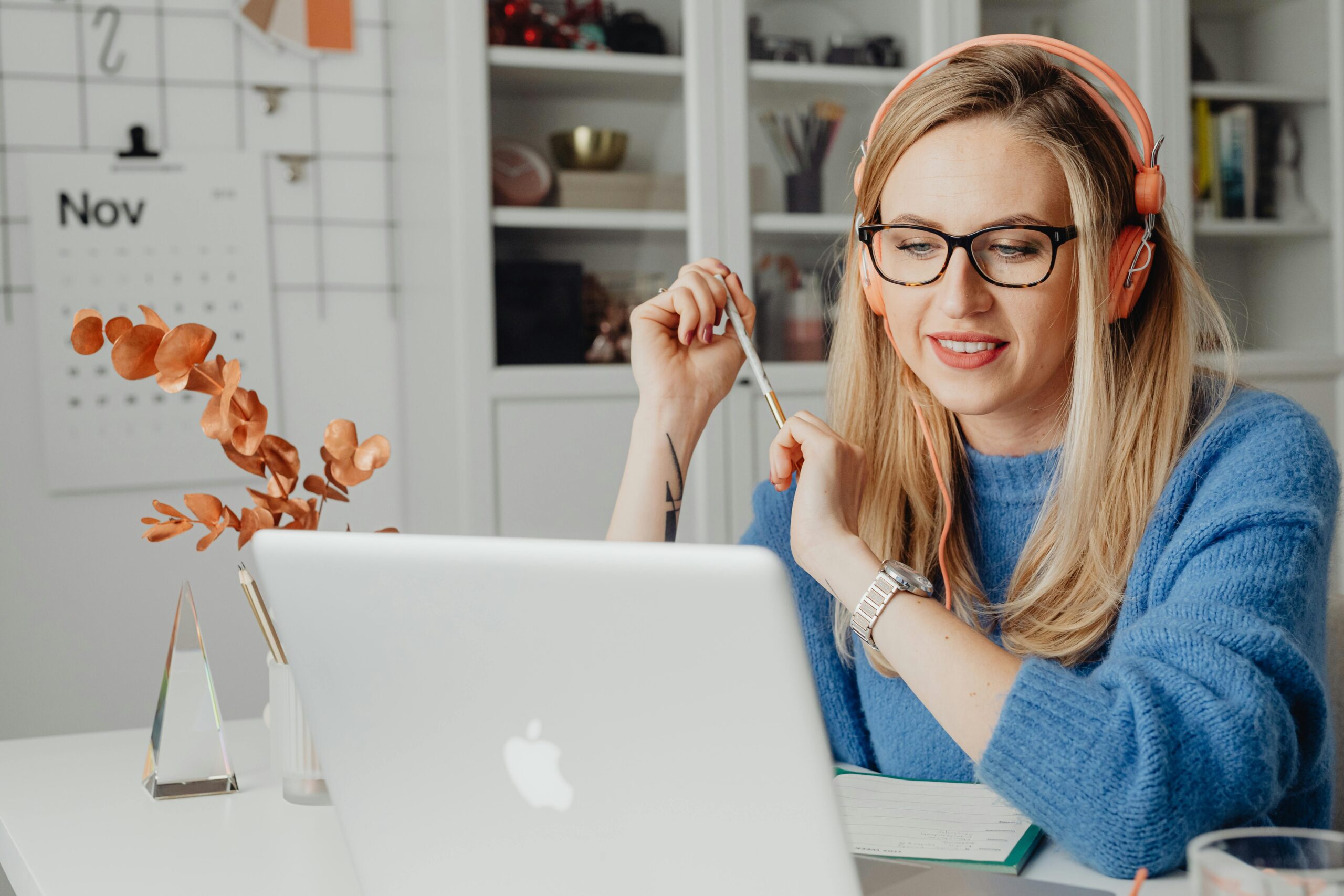 A young woman in headphones working on her laptop from home, embodying modern remote work lifestyle.