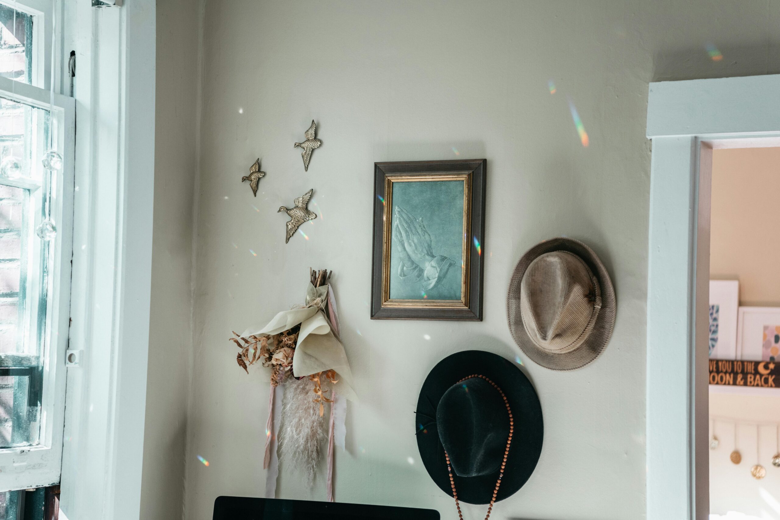 Charming vintage interior featuring hats, wall art, and dried floral decor.