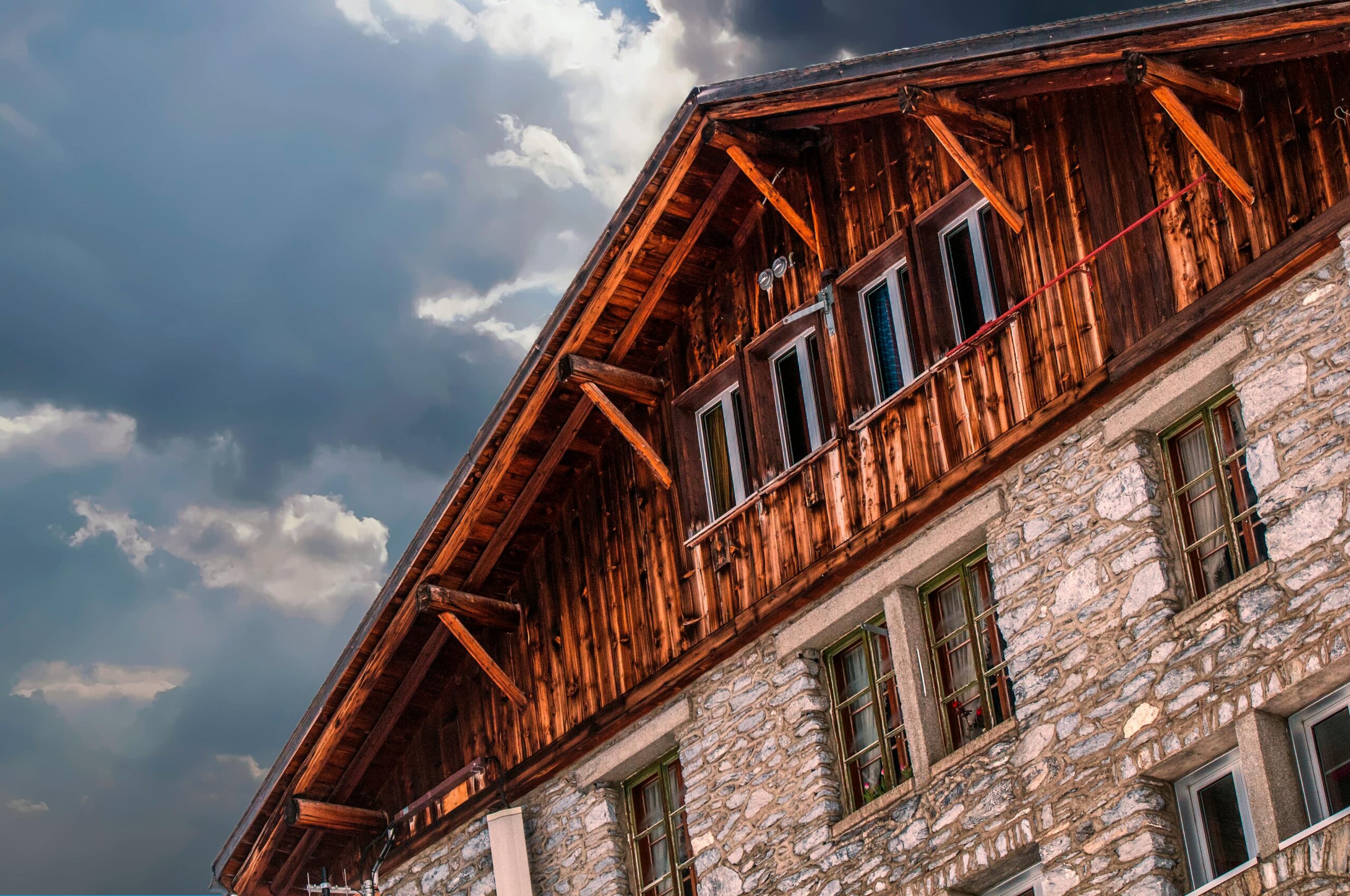 Close-up of a rustic house with wooden and stone facade against a cloudy sky showcasing traditional architecture.