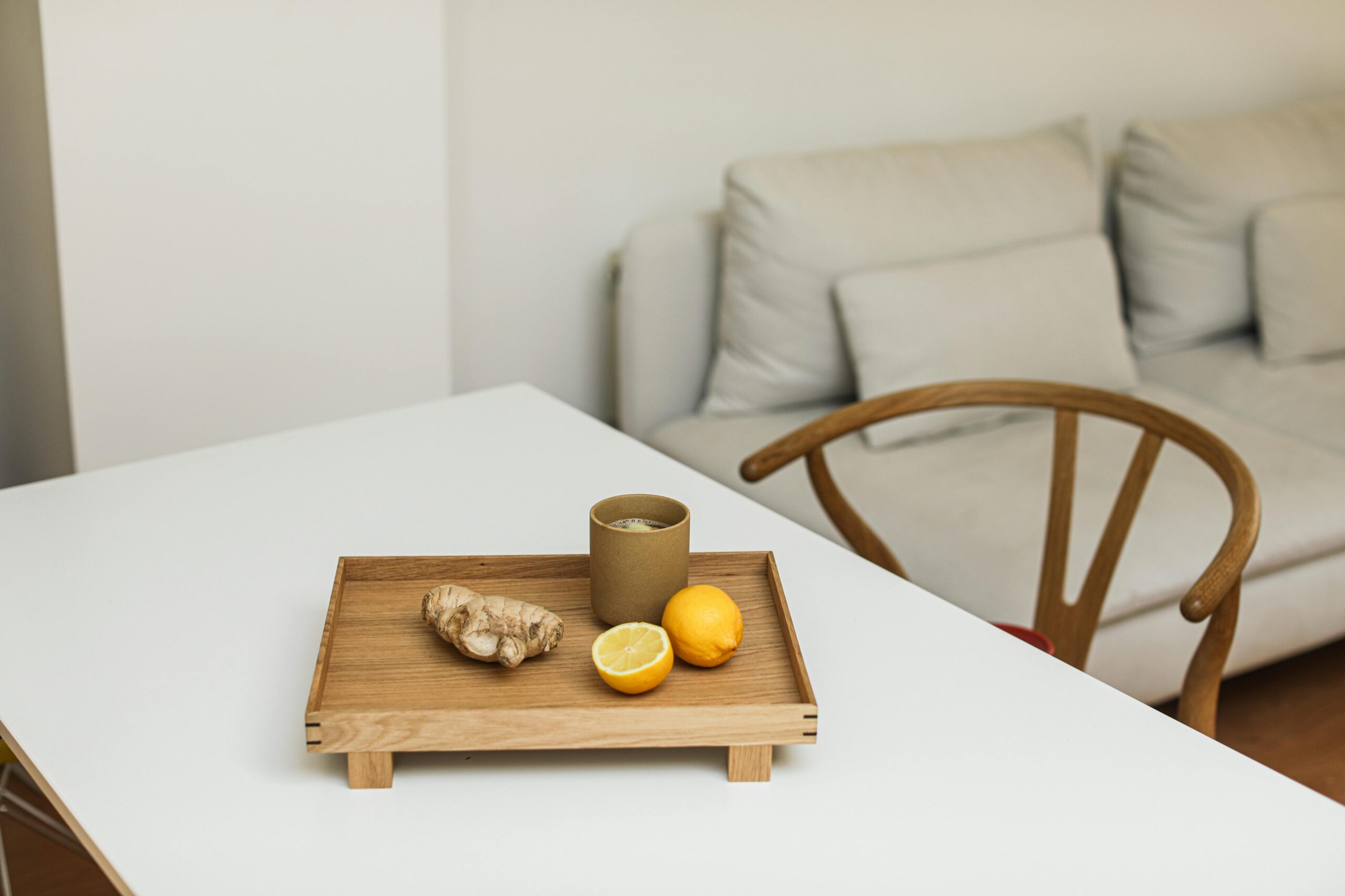 Elegant minimalist composition featuring lemons and ginger on a wooden tray indoors.