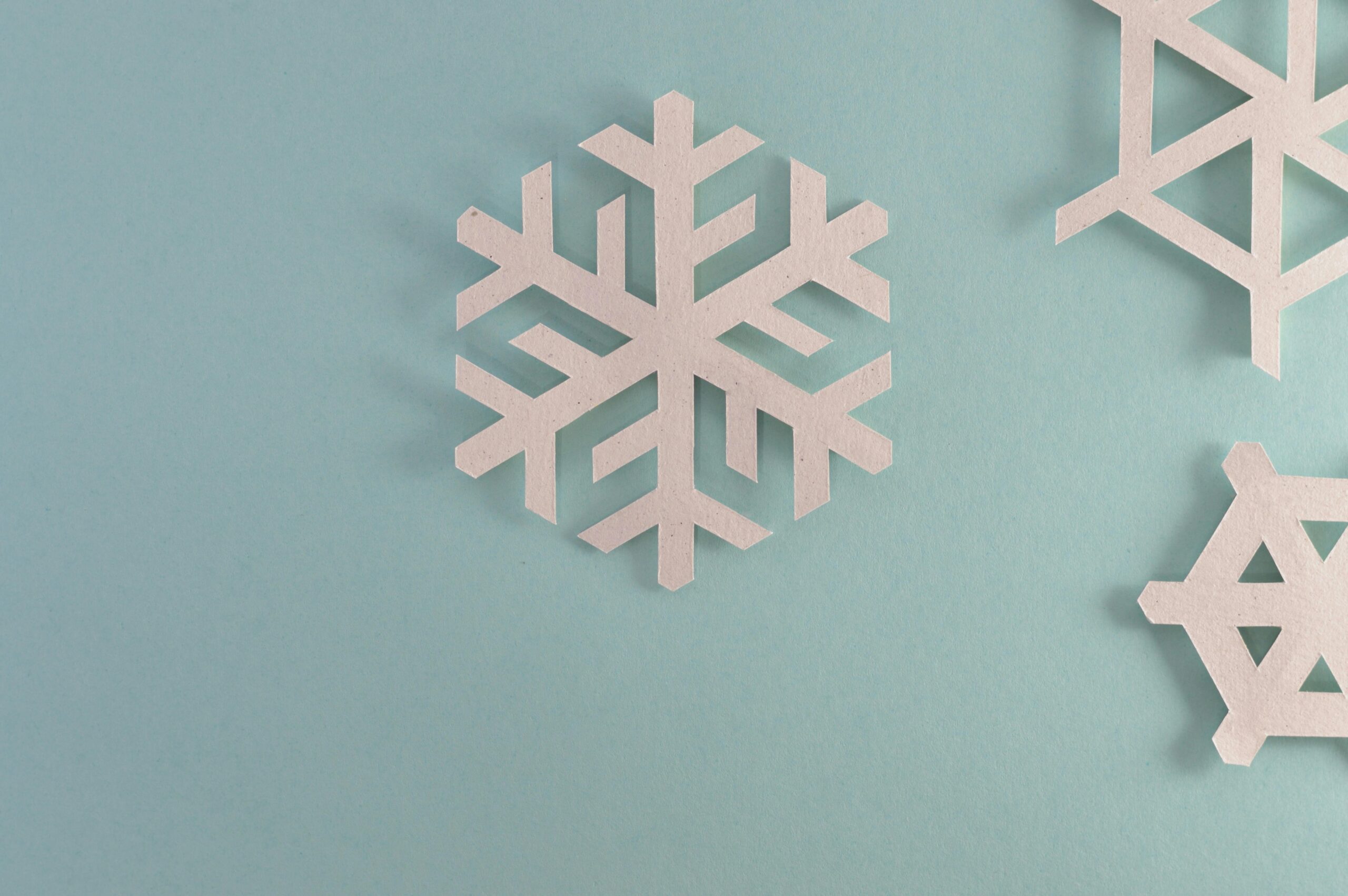 Elegant paper snowflakes on a pale blue background, perfect for winter or holiday decor.