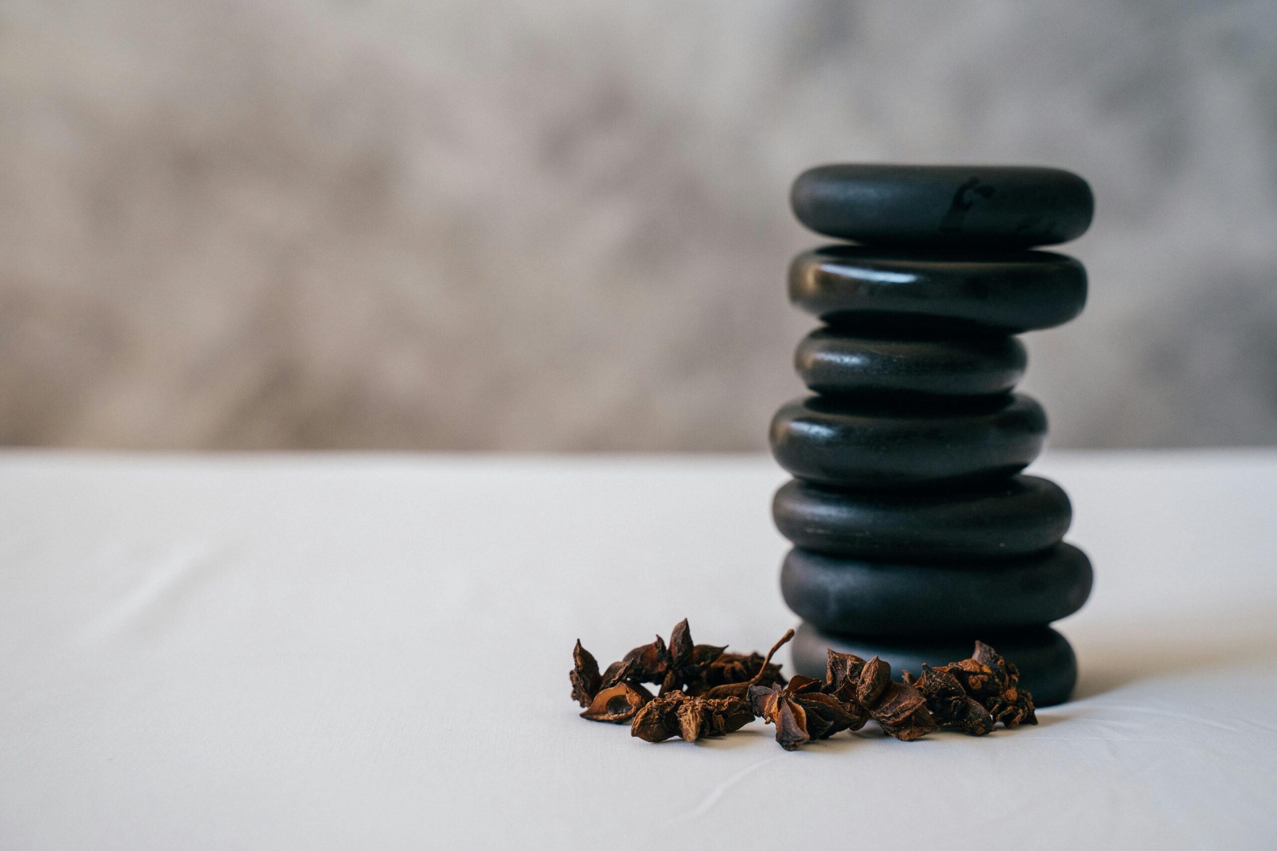 A stack of smooth stones balanced with aromatic star anise on a white surface, creating a serene atmosphere.