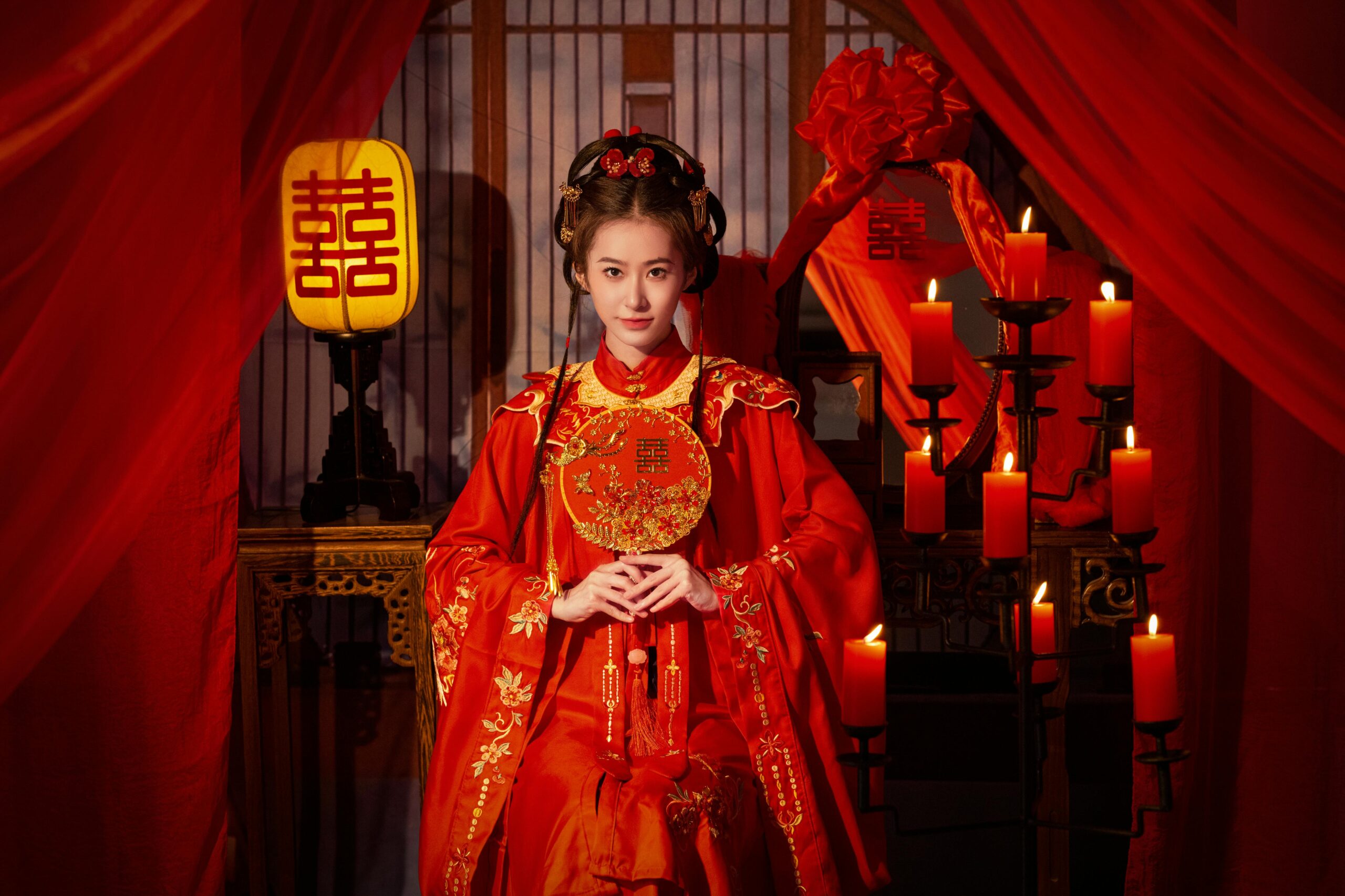 Traditional Chinese bridal portrait with red dress and candles, showcasing cultural elegance.