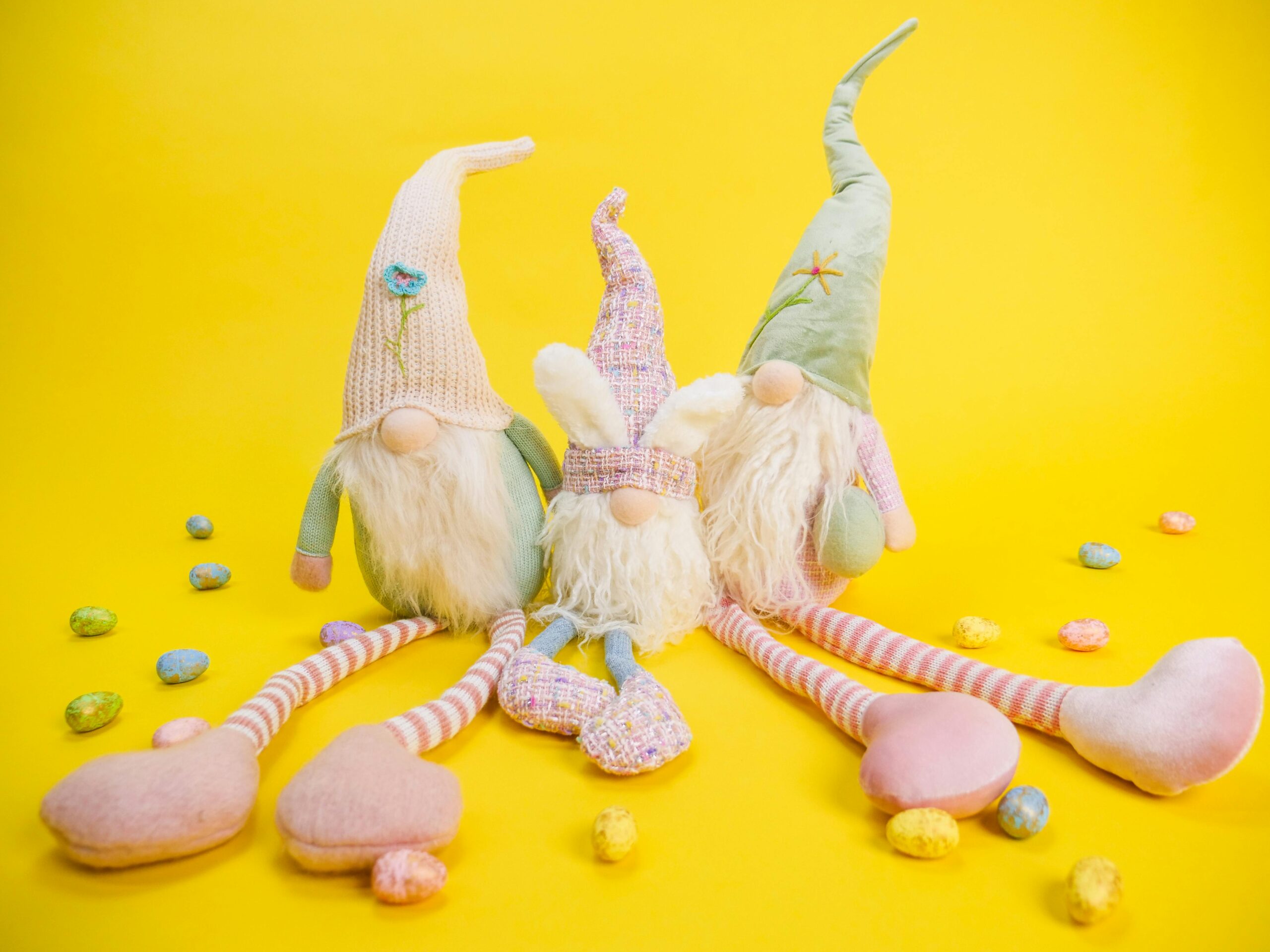 Charming Easter scene with gnomes and colorful eggs on a vibrant yellow backdrop.