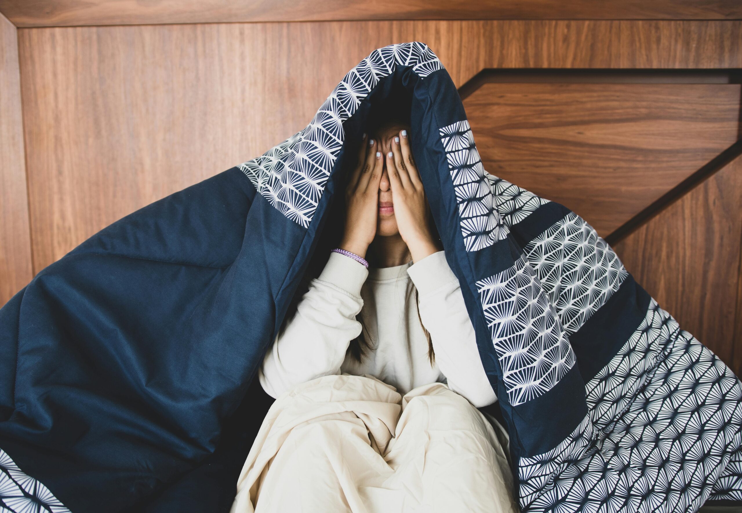 Person hiding under a blanket, creating a cozy and intimate indoor atmosphere.