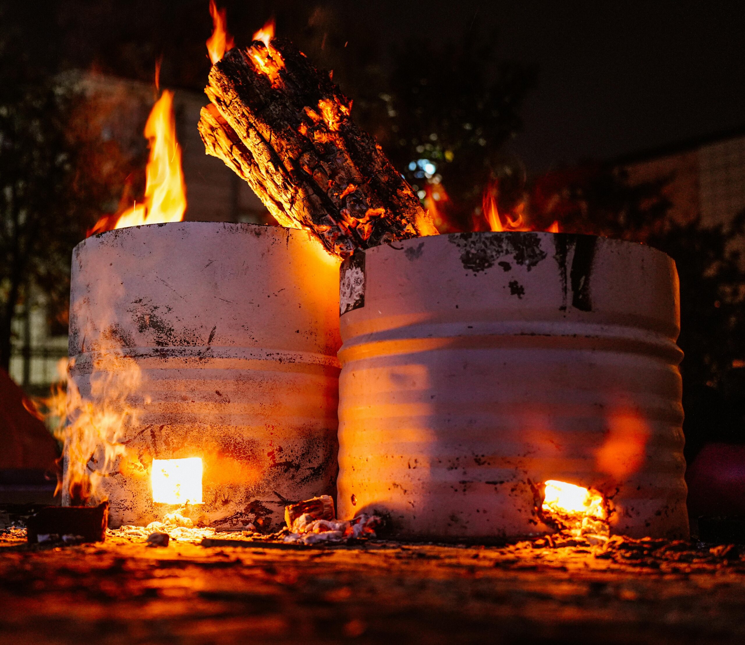 Two barrels with crackling fire logs illuminate the night with a warm glow.