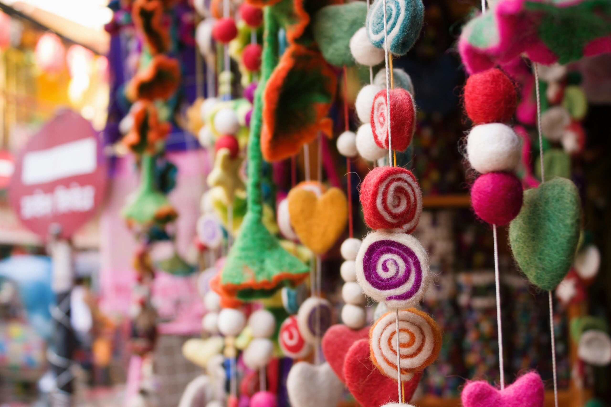 Vibrant hanging decorations made of threads in a Nepalese outdoor market stall.