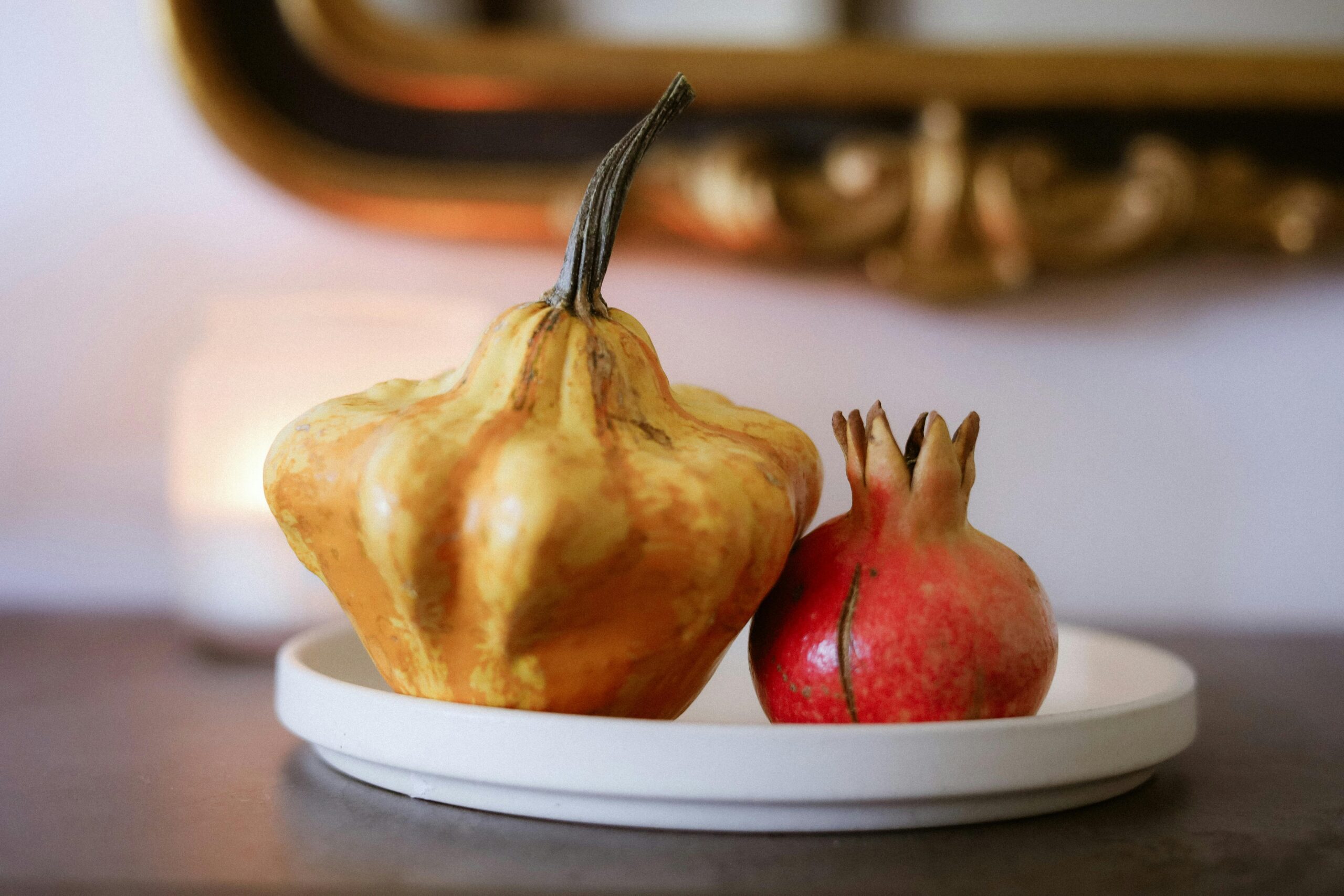 Warm autumn still life featuring gourd and pomegranate indoors.