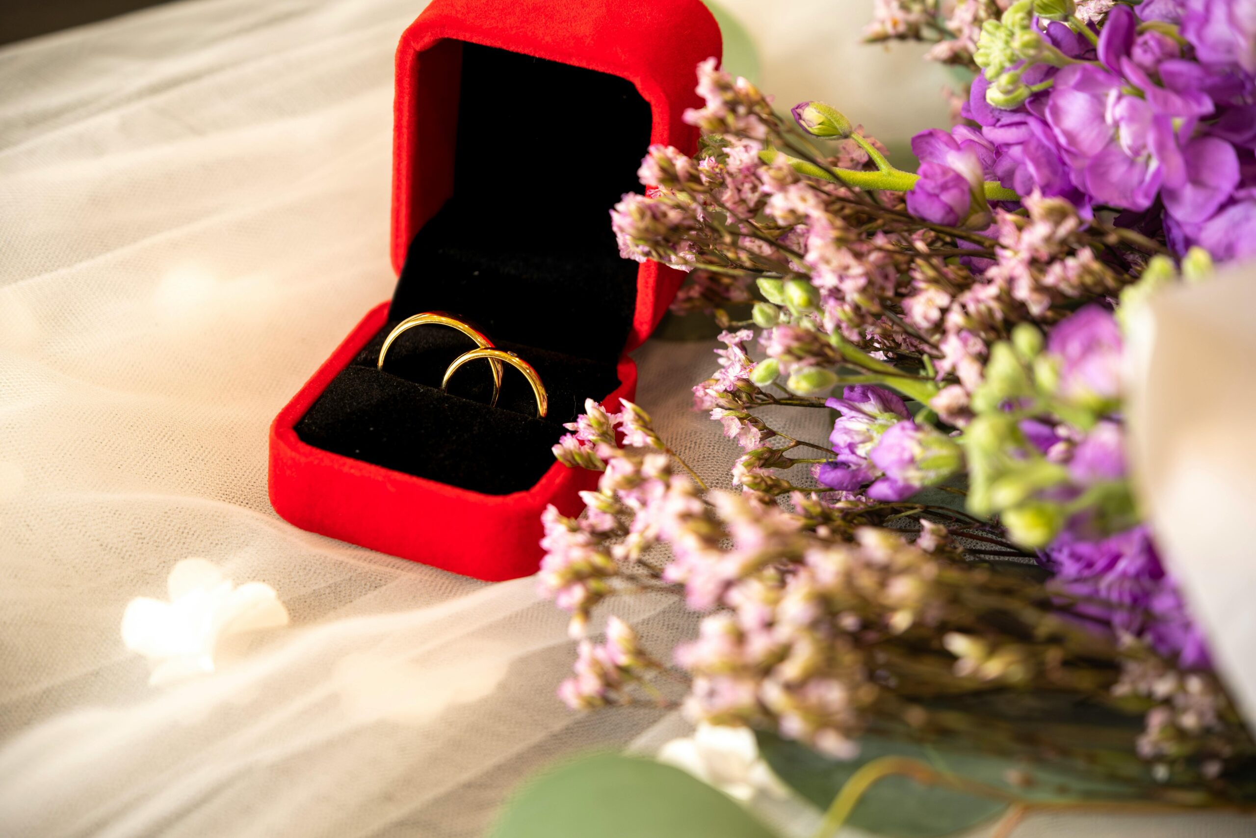 Wedding rings in a red velvet box with lavender flowers, symbolizing love.